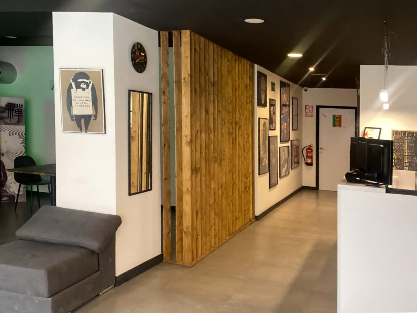 The reception desk and modern interior at Four Twenty cannabis club in Valencia, featuring a wooden slat partition, framed wall art, and a grey lounge chair.