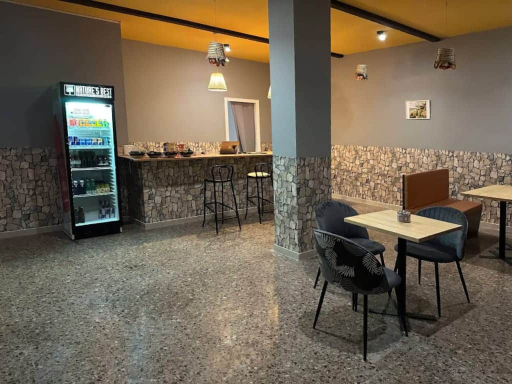 Interior of Magura cannabis club in Valencia, featuring a stone-textured bar counter, terrazzo flooring, modern seating, and a refrigerated beverage display.