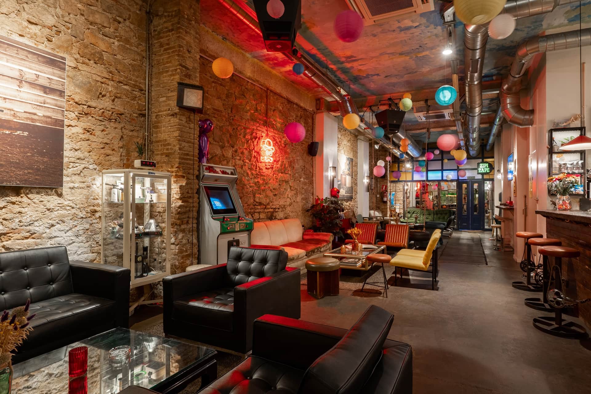 At Dr. Dou Barcelona social cannabis club, interior features leather armchairs and a retro arcade machine