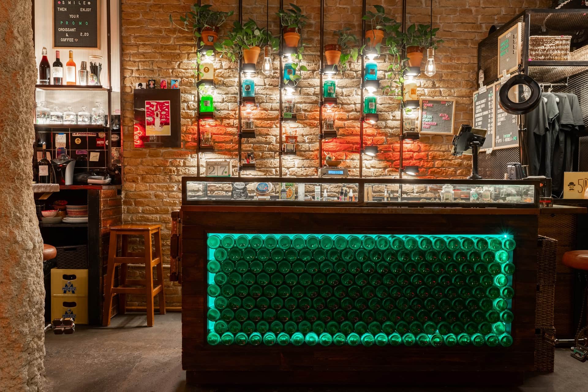 Bar counter with green lighting and brick walls at the social cannabis club Dr. Dou Barcelona Title: Dr. Dou