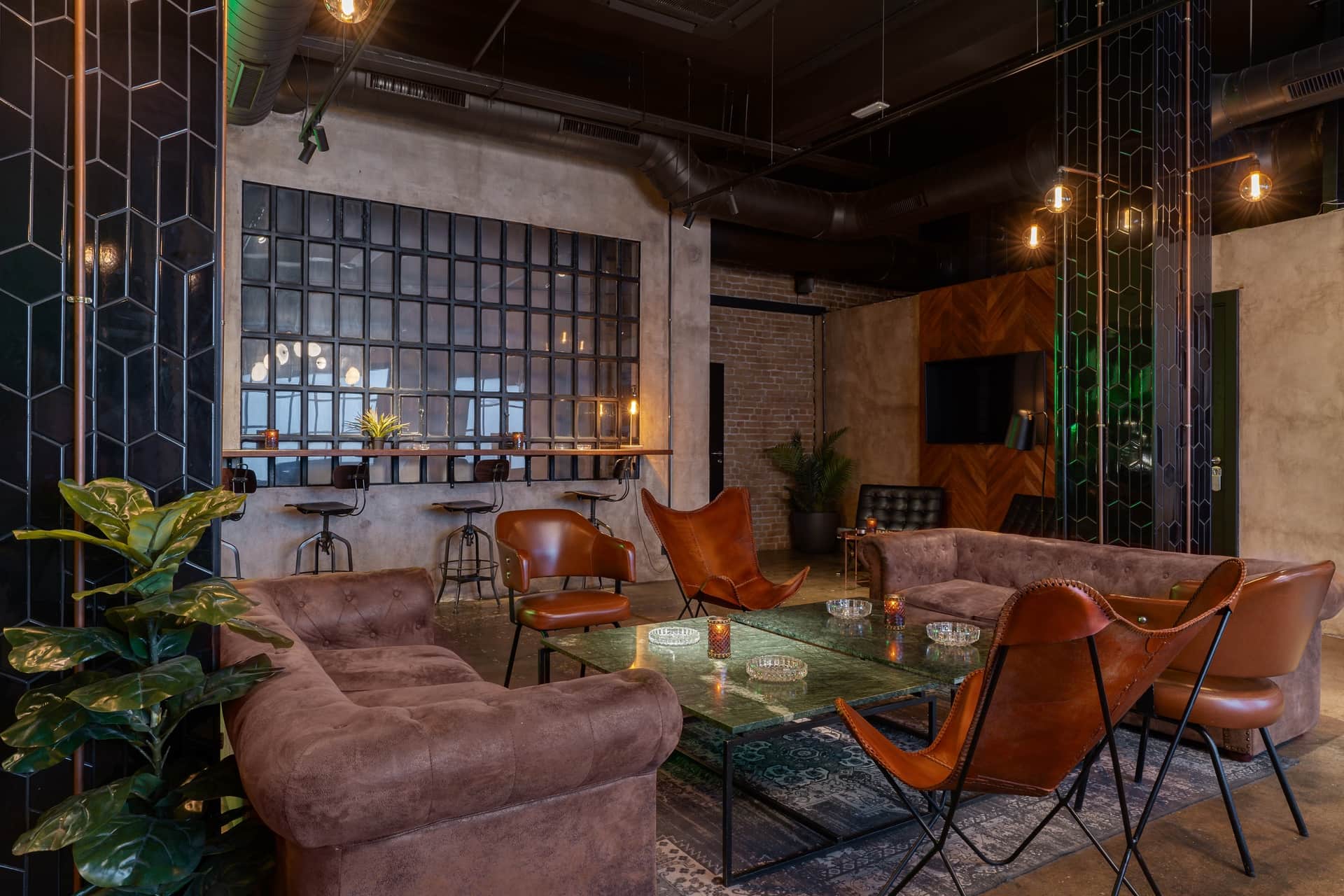 Dr. Resin Barcelona social cannabis club — modern lounge with brown sofas, glass tables, and green plants