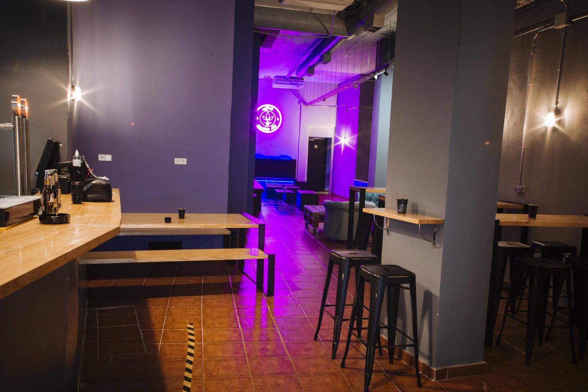 Bar and seating area of the cannabis social club Enjoint in Madrid with neon lighting