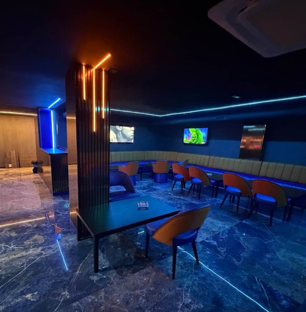Interior of Lux Lounge social club in Marbella with blue neon lighting, upholstered benches and marble floor.