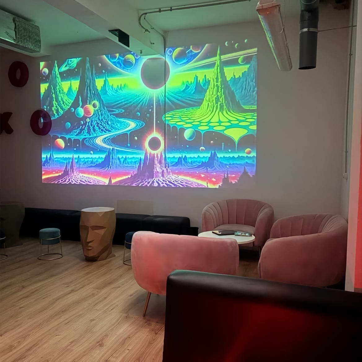 Lounge with velvet armchairs and large psychedelic wall projection in the Mística Social Club Madrid