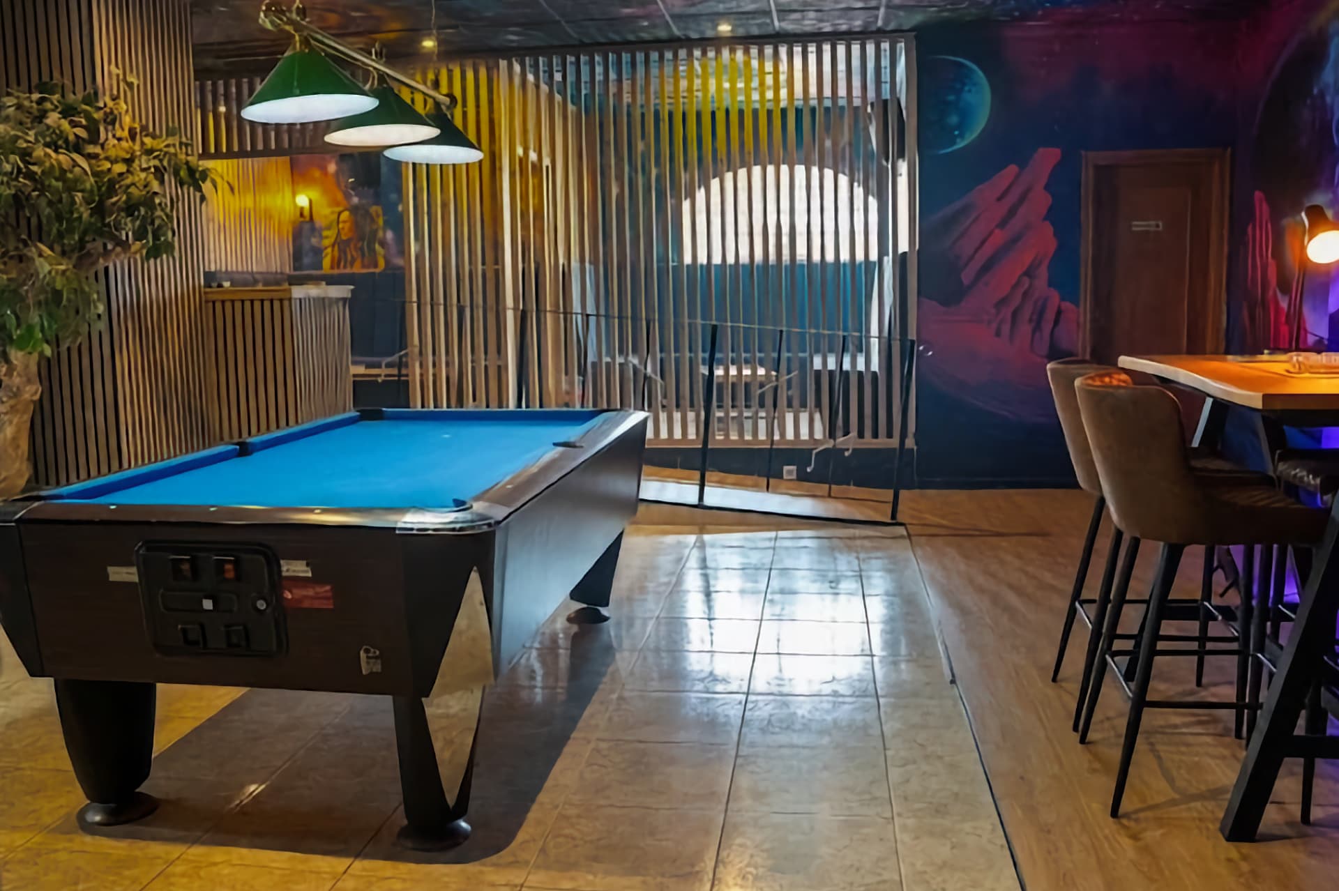 Pool table in the social cannabis club Sky Alicante with space-themed wall mural and wooden partitions