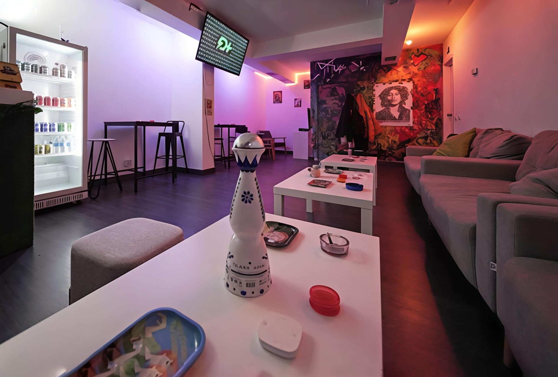 Lounge area at Valhalla cannabis club in Madrid with blue and orange neon lighting, low coffee tables, and graffiti wall art.